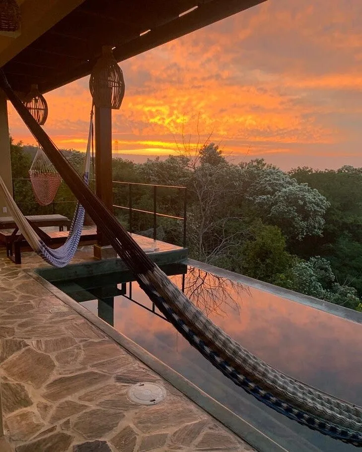 Alberca infinita al atardecer con hamaca y vista a la selva de Mazunte