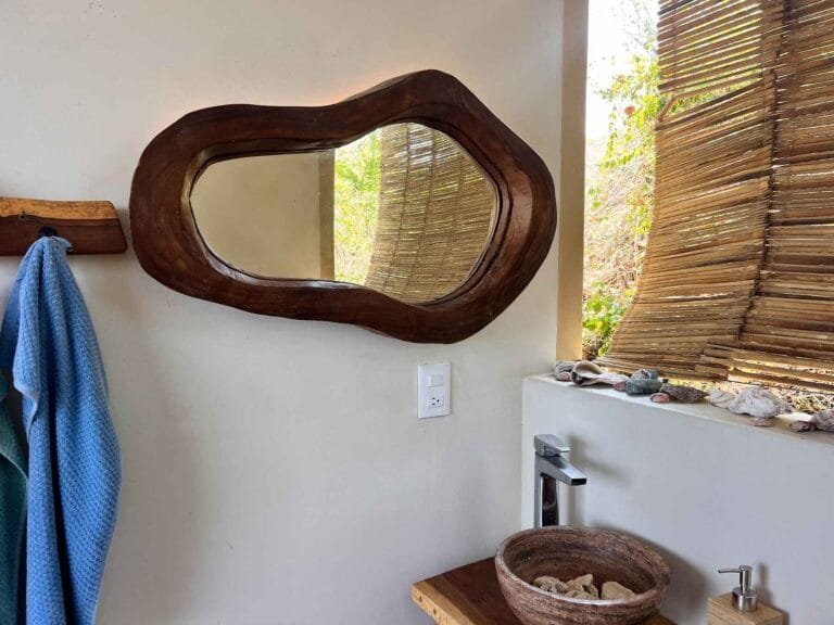 Shared bathroom with organic wood mirror and reed blind