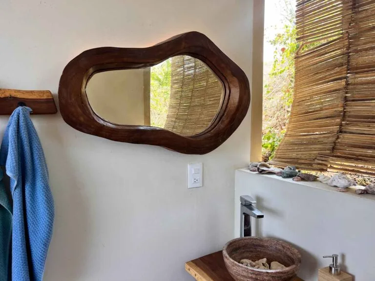 Baño común con espejo de madera orgánica y persiana de carrizo