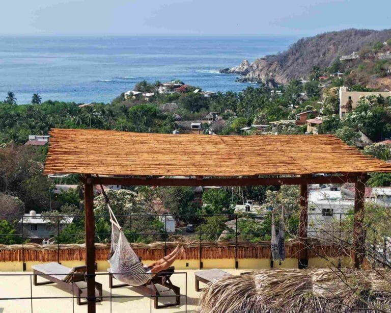Silla colgante bajo la pérgola de la azotea con vista al mar en Mazunte