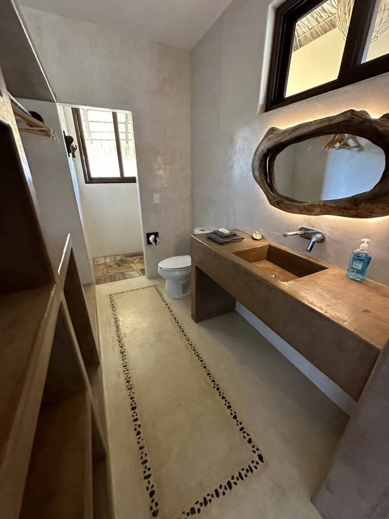 Baño privado de la Suite 1 con espejo de madera orgánica y lavabo de concreto