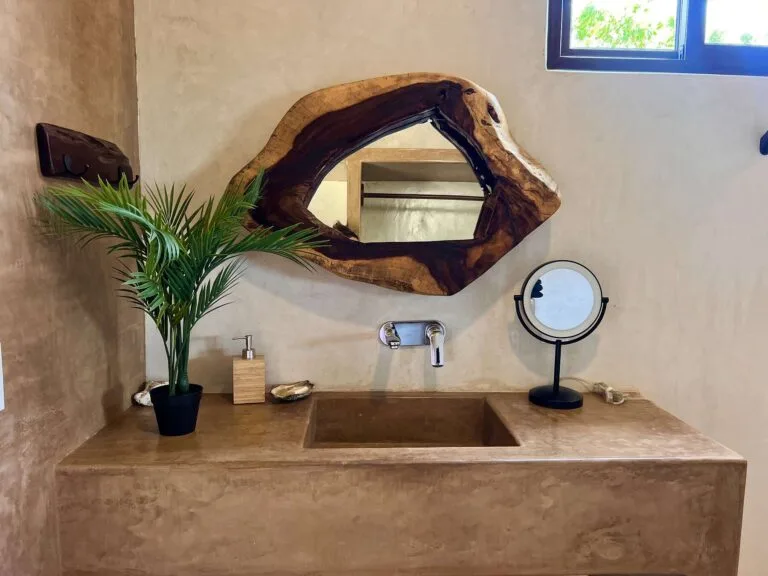 Baño privado de la Suite 3 con espejo de madera y lavabo de concreto