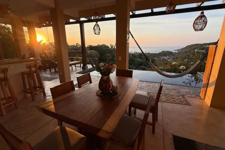 Comedor al aire libre de Casa La Vista al atardecer con hamaca y vista al mar