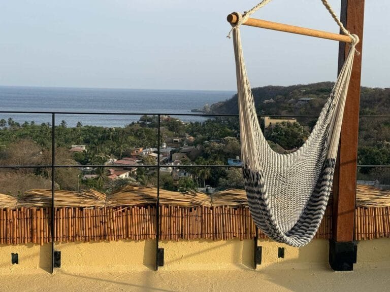 Hanging chair on the rooftop with a bamboo fence and ocean view at Casa La Vista, Mazunte