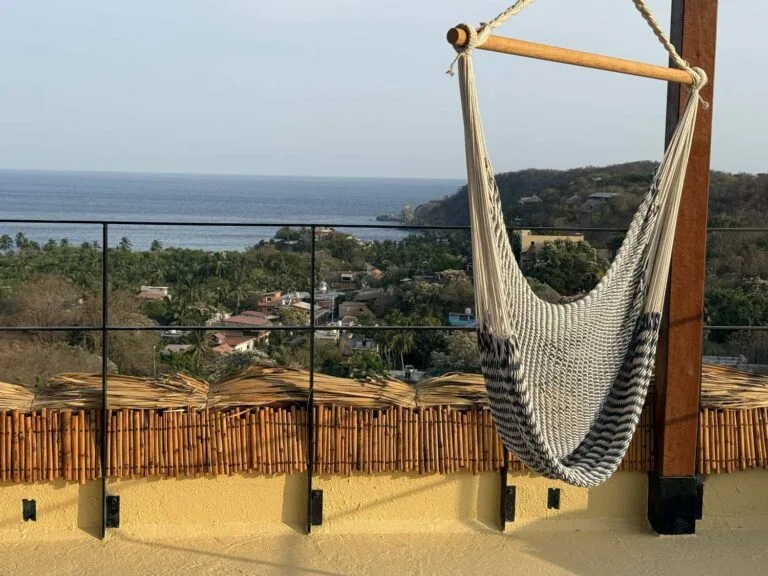 Silla colgante en la azotea con cerca de bambú y vista al mar en Casa La Vista, Mazunte