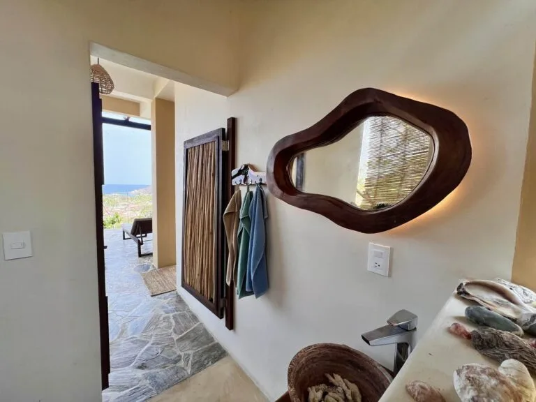 Baño común con espejo de madera y puerta abierta hacia la terraza en Casa La Vista