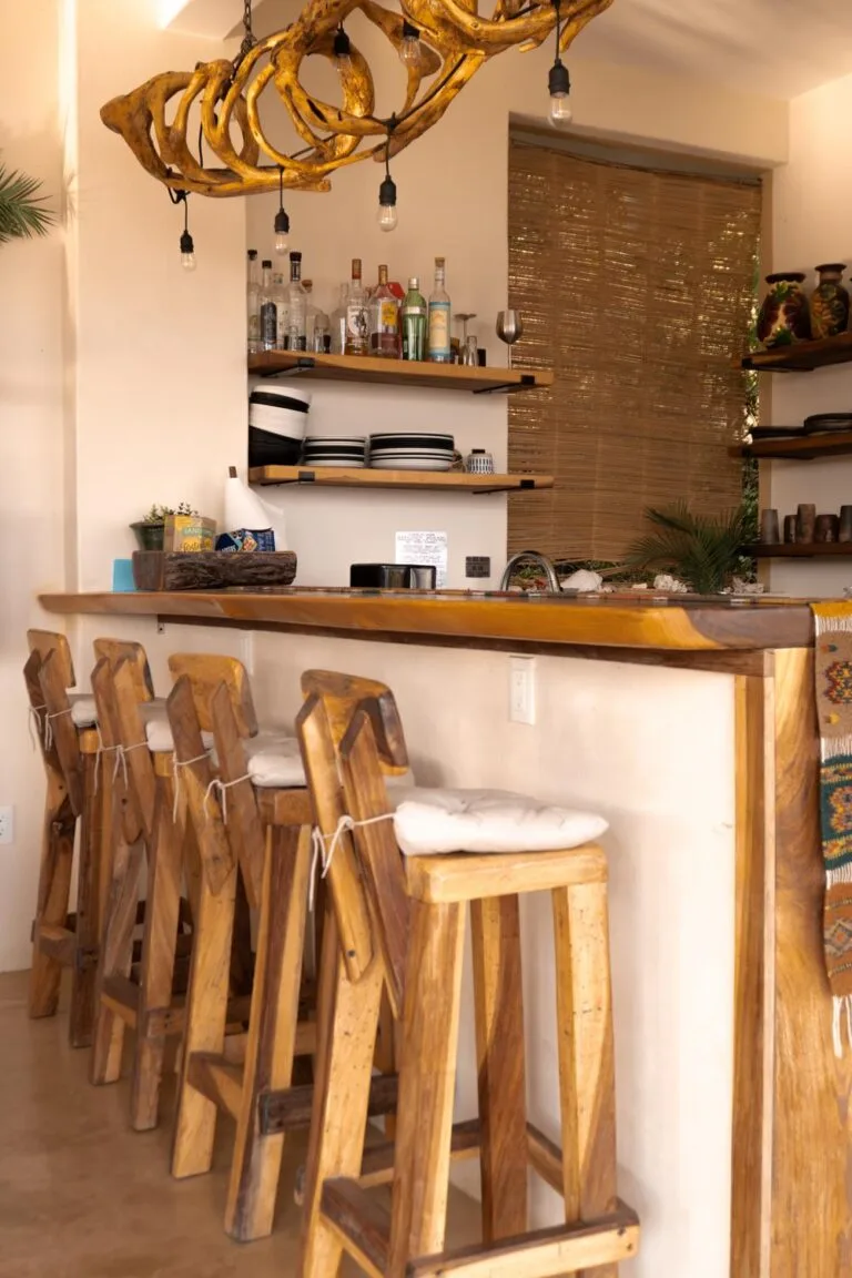 Área de bar con taburetes de madera y repisa de licores en Casa La Vista, Mazunte