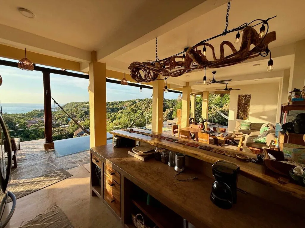 Barra de cocina con candelabro de madera y vista al mar al atardecer en Casa La Vista, Mazunte