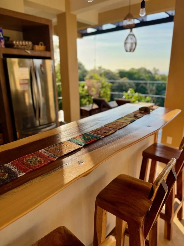 Barra de desayuno con taburetes de madera y refrigerador de acero en la cocina de Casa La Vista