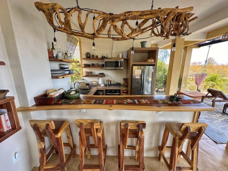 Open kitchen with a wooden bar, stools and a driftwood chandelier overlooking the sea at Casa La Vista, Mazunte