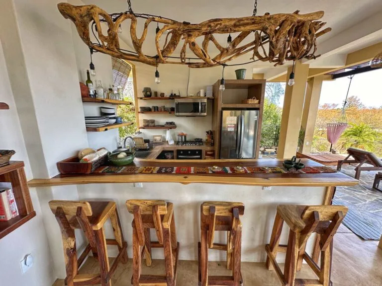 Cocina abierta con barra de madera, taburetes y candelabro de madera flotada con vista al mar en Casa La Vista, Mazunte