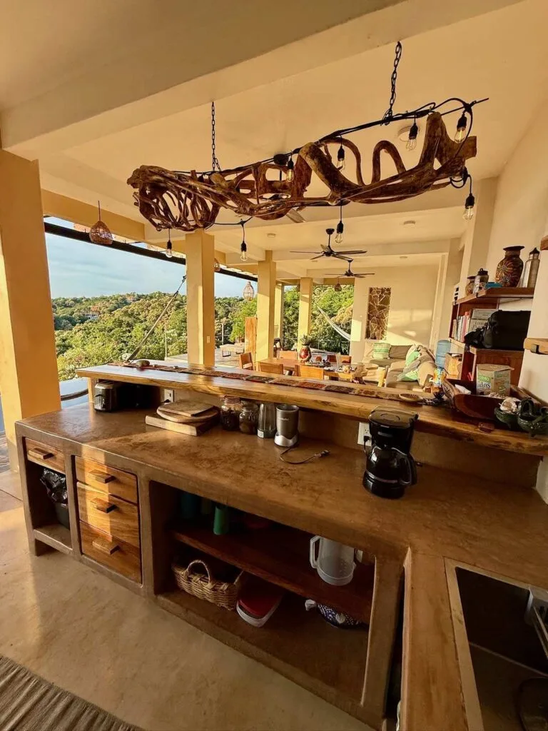 Cocina con encimera y candelabro de madera flotada con luz dorada en Casa La Vista, Mazunte