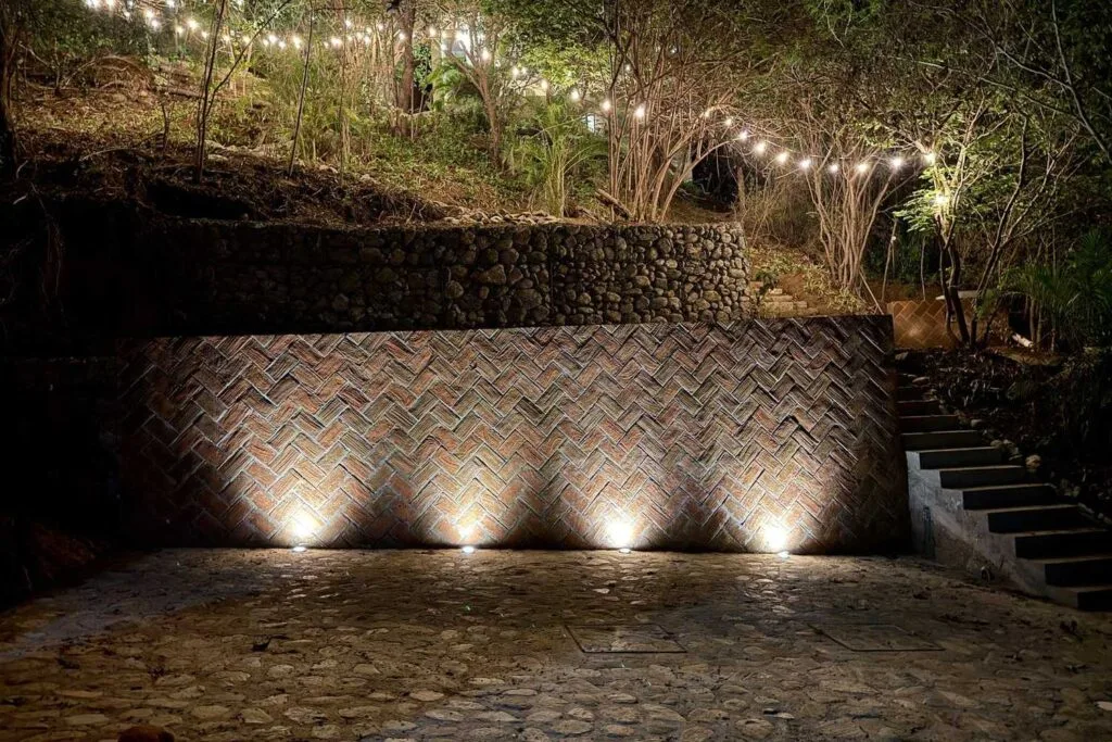 Entrada nocturna a Casa La Vista con luces cálidas y muro de piedra