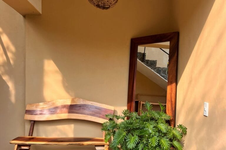 Entrada de Casa La Vista con banca de madera, espejo grande y planta