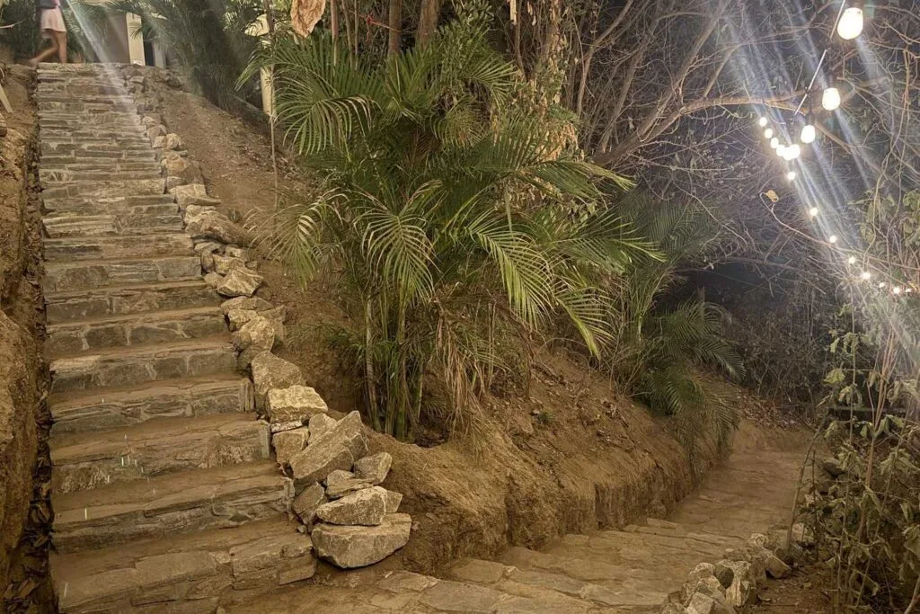 Escalera de piedra iluminada con luces que sube hacia Casa La Vista