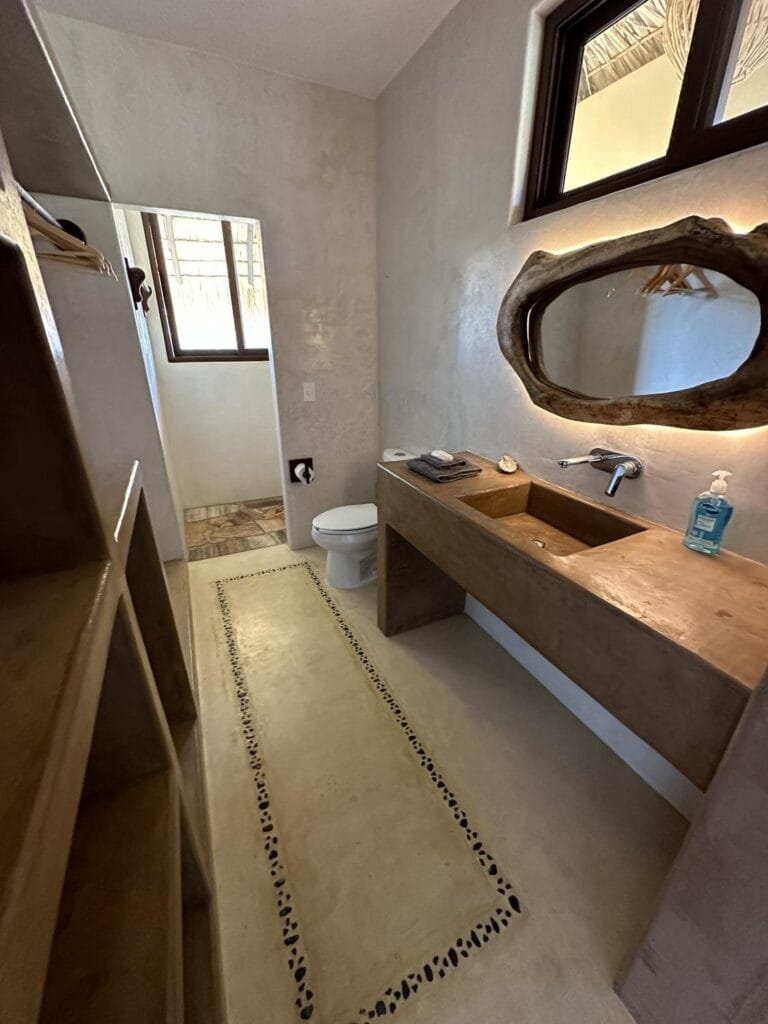 Baño de la Suite 1 con espejo de madera y lavabo de concreto en Casa La Vista