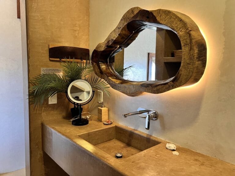 Baño de la Suite 2 con espejo de madera con luz y lavabo de concreto pulido
