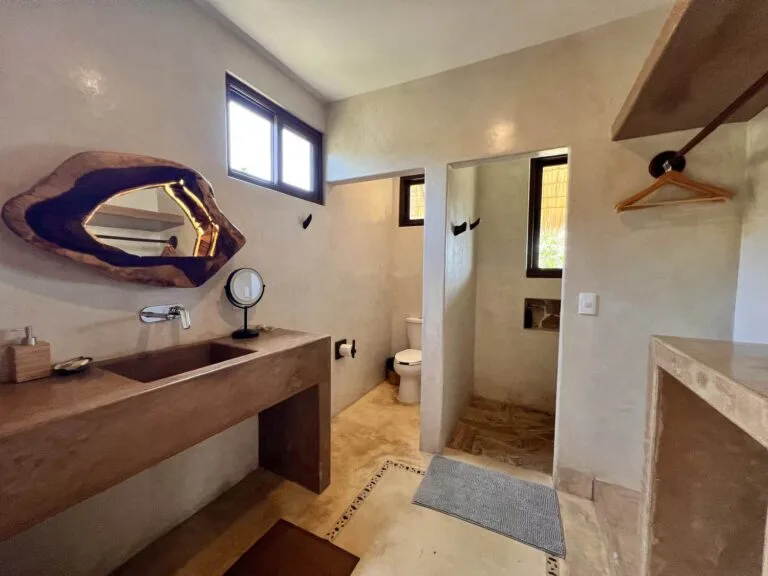 Baño de la Suite 3 con lavabo de concreto pulido, espejo de madera y regadera