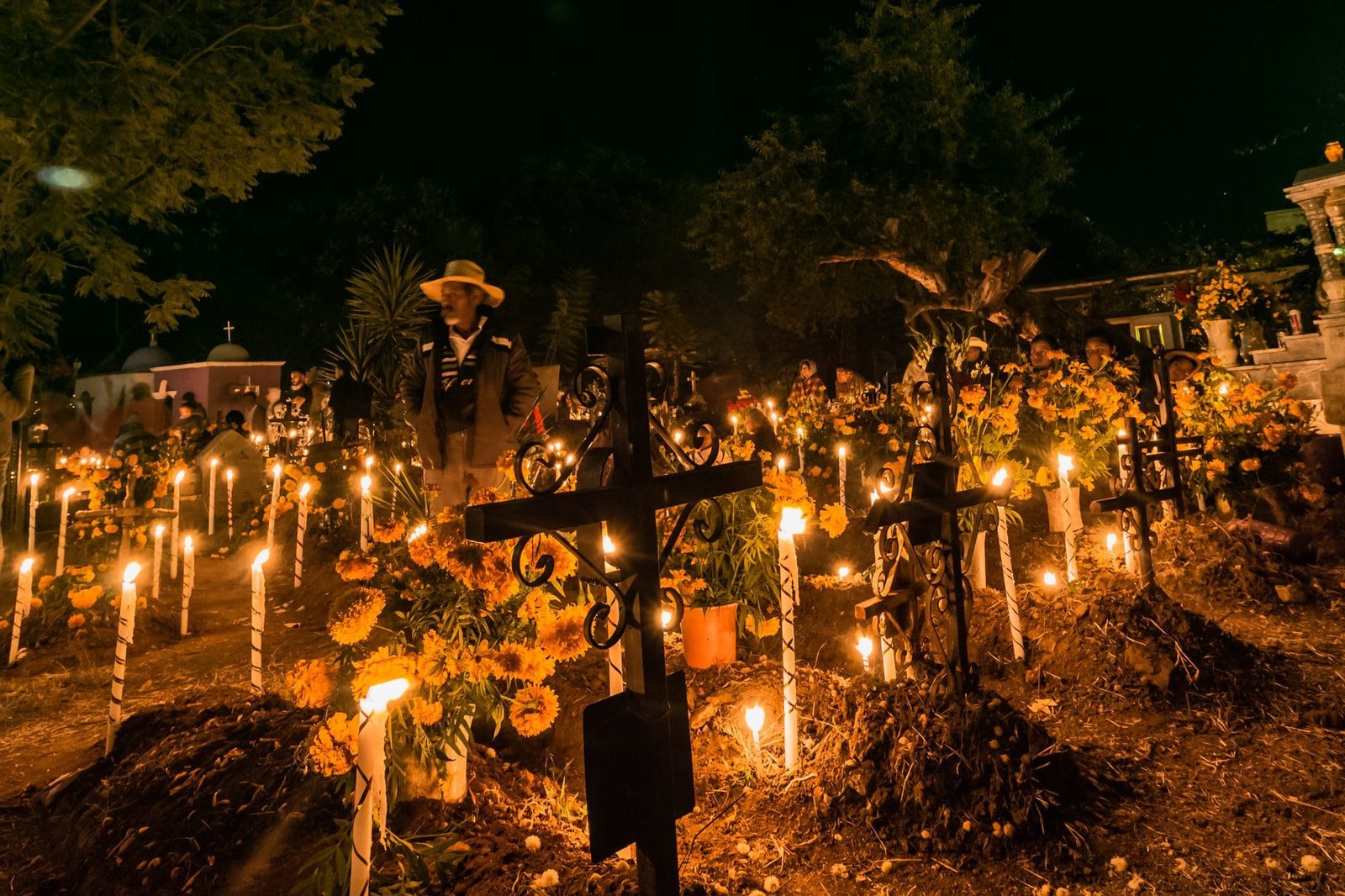 Cruces de hierro, velas y flores de cempasúchil en un panteón de Oaxaca durante la noche de Día de Muertos