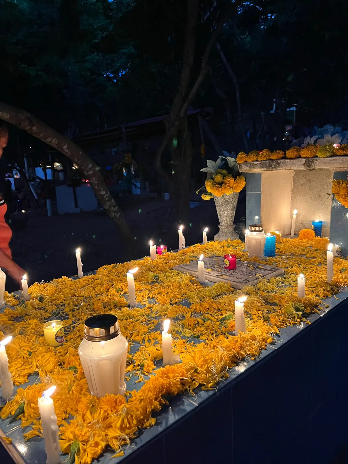 Tumba cubierta de pétalos de cempasúchil con velas encendidas en el panteón de Mazunte