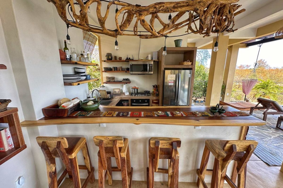 Cocina abierta con barra de madera, taburetes y candelabro de madera flotada con vista al mar en Casa La Vista, Mazunte